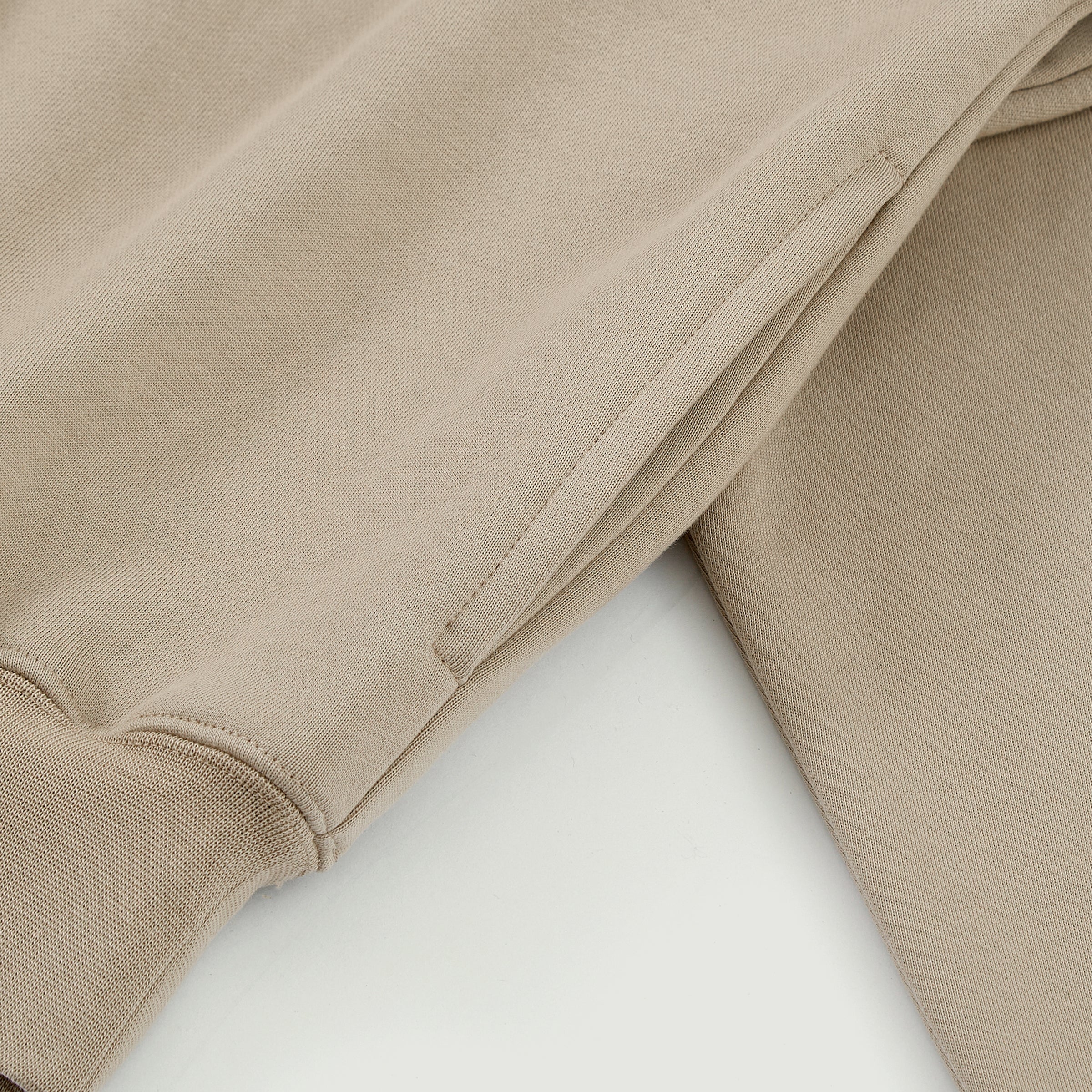 Close-up of the cream Soul Supremacy Snap Button Collar Hoodie Encoded Motifs showing the side pocket and washed fabric texture
